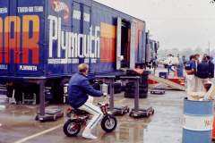 Dan Gurney on a mini-bike in the pits.